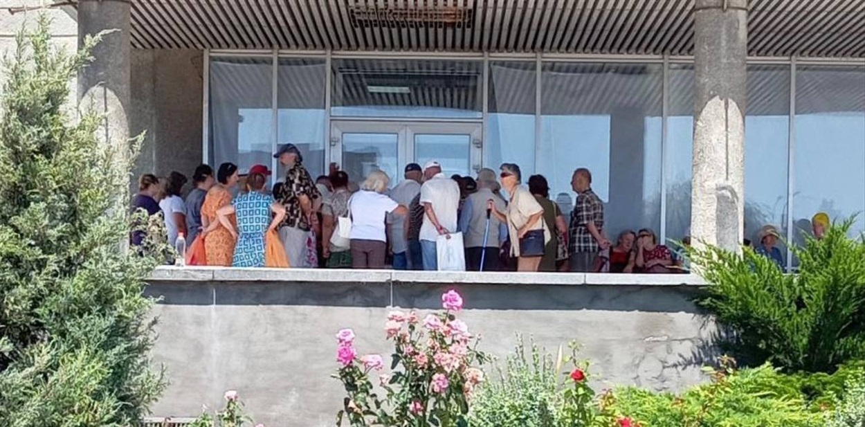 Пенсіонери стоять у черзі за продуктовими наборами, які видають окупанти у Бердянському палаці культури